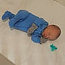 Elijah joined the competition — help win amazing prizes! baby, newborn, sleeping, blue_onesie, mittens, pacifier, bed, white_bed, infant, peaceful, cute, child, person, resting, soft_lighting, indoors, portrait, head, small, cozy