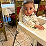 baby, child, high_chair, restaurant, table, chair, floor, person, clothing, bow_tie, face, eyes, hand, tile_floor, waiter, interior, dining, decor, furniture, sitting