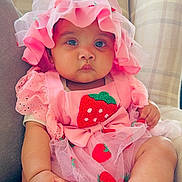 Liyana joined the competition — help win amazing prizes! baby, infant, pink_clothing, strawberry, hat, cute, sitting, couch, indoors, child, portrait, chubby, feet, curious, soft_lighting, textile, fabric, cute_outfit, baby_fashion, relaxed