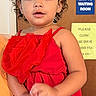 child, toddler, girl, portrait, red_dress, ruffles, curly_hair, brown_hair, wide_eyes, indoor, hospital, waiting_room, door, sign, standing, adult_hand, closeup, colorful, cute, photography