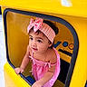 Jener joined the competition — help win amazing prizes! child, toddler, girl, portrait, smiling, pink_outfit, headband, bow, yellow_car, ride_on_car, vehicle, indoor, play_area, sitting, looking_away, dark_hair, earring, necklace, bright_colors, candid_photo