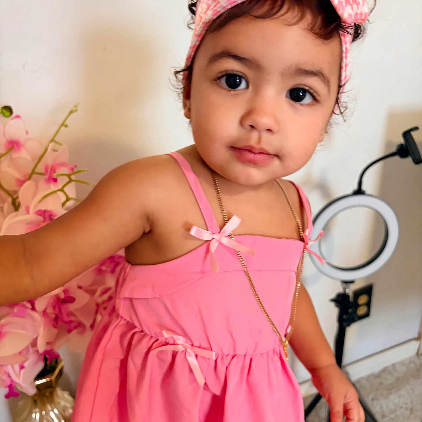 Jener joined the competition — help win amazing prizes! child, toddler, portrait, pink_dress, headband, bow, curly_hair, brown_eyes, looking_at_camera, indoors, ring_light, flowers, vase, mirrors, home_decor, photography, fashion, jewelry, standing, smiling