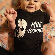 Ryan is registered to the contest to win money with this photo: baby, infant, smiling, onesie, black_clothing, unicorn_blanket, hand, face, cute, lying_down, child, happy, apparel, patterned_blanket, small_hand, baby_garment, infant_clothing, portrait, indoors, soft_texture