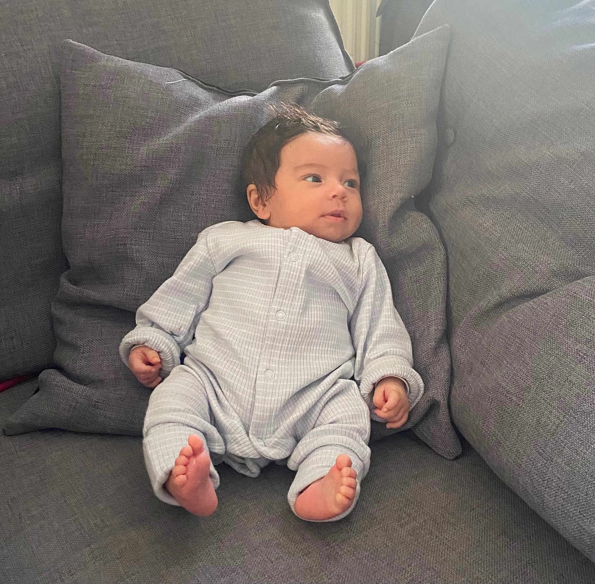 Marley a rejoint le concours — aidez-le/la à gagner de superbes lots ! baby, infant, couch, cushion, gray, onesie, foot, hand, face, person, indoor, relaxing, cute, child, portrait, seated, soft, comfort, home, cozy