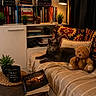 blanket, book, bookshelf, cat, coffee_mug, couch, cozy, decor, gray_cat, home, indoor, lamp, pillow, plant, reading_nook, relaxing, table, teddy_bear, warm_light, wooden_floor