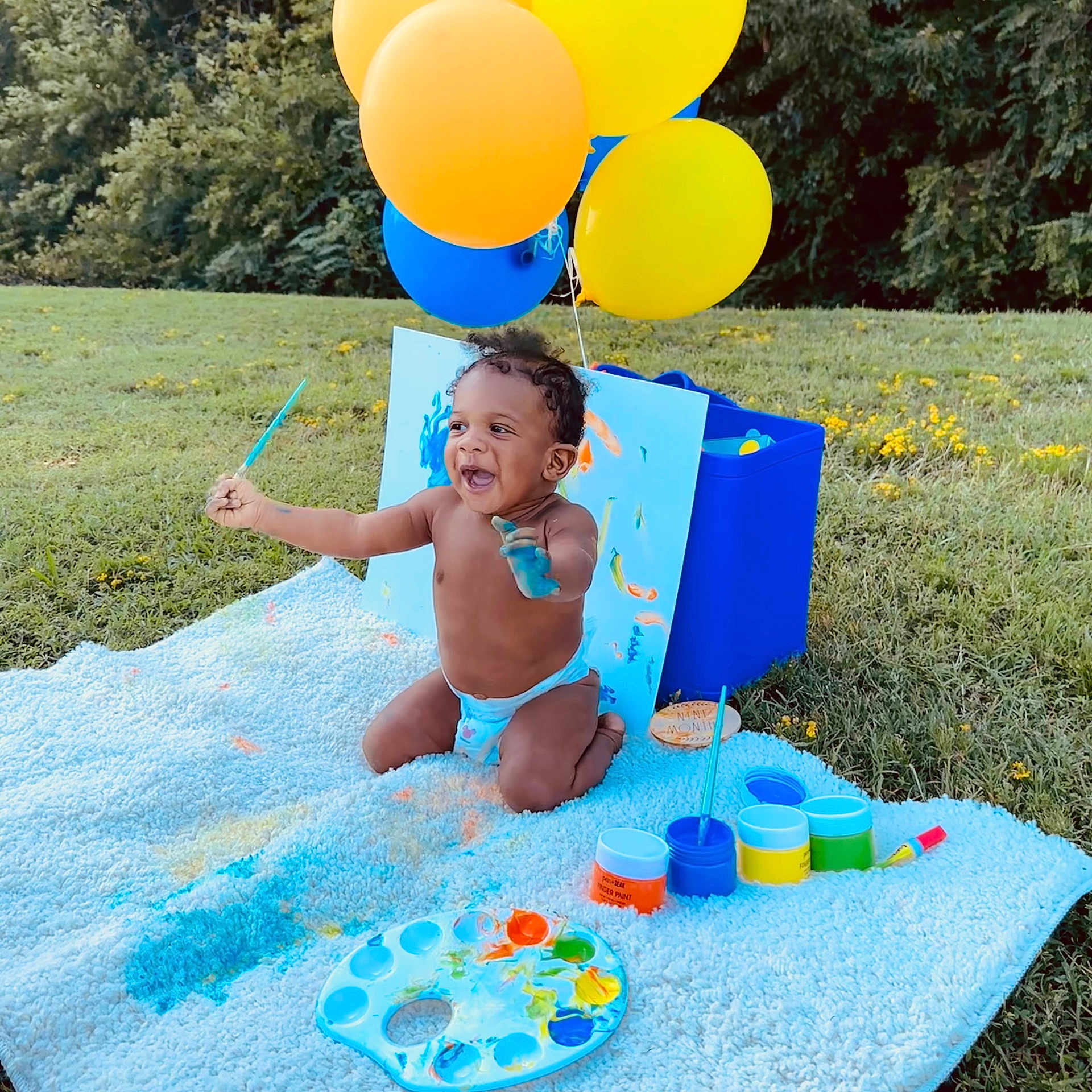 Jonathan is registered to the contest to win money with this photo: toddler, child, painting, paint, balloons, blanket, outdoor, grass, happy, smiling, art_supplies, palette, brush, colorful, nature, play, sunlight, expression, messy, diaper