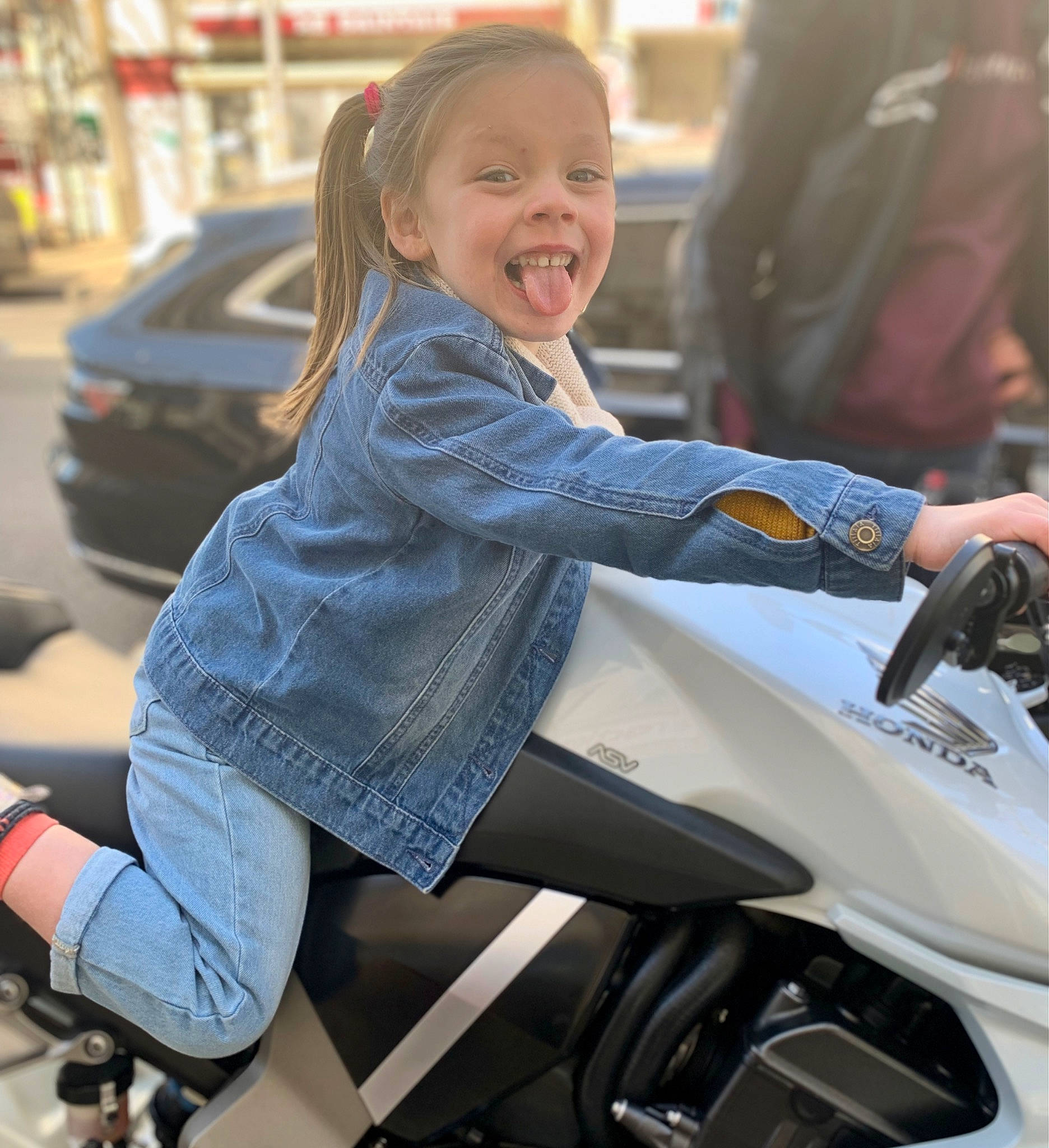 Adèle a rejoint le concours — aidez-le/la à gagner de superbes lots ! automotive_design, automotive_exterior, automotive_lighting, automotive_tire, automotive_wheel_system, blond, fun, hairstyle, hand, happy, human_leg, motor_vehicle, motorcycle, person, personal_protective_equipment, smile, standing, thigh, tire, toddler