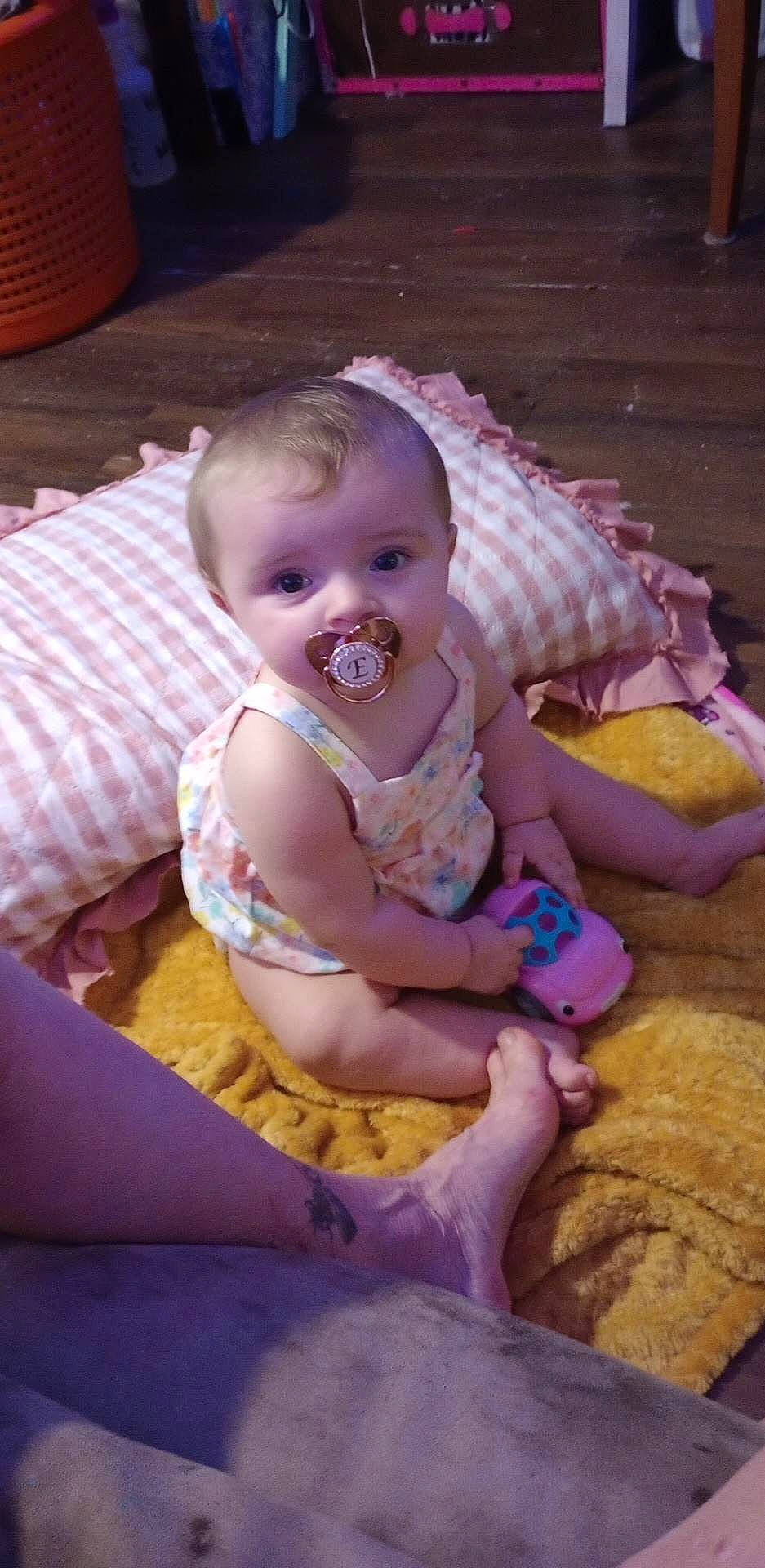 Evelynn is registered to the contest to win money with this photo: baby, baby_toddler_clothing, cheek, child, comfort, eye, flooring, fun, happy, iris, mammal, pattern, person, pink, purple, room, sitting, skin, smile, toddler