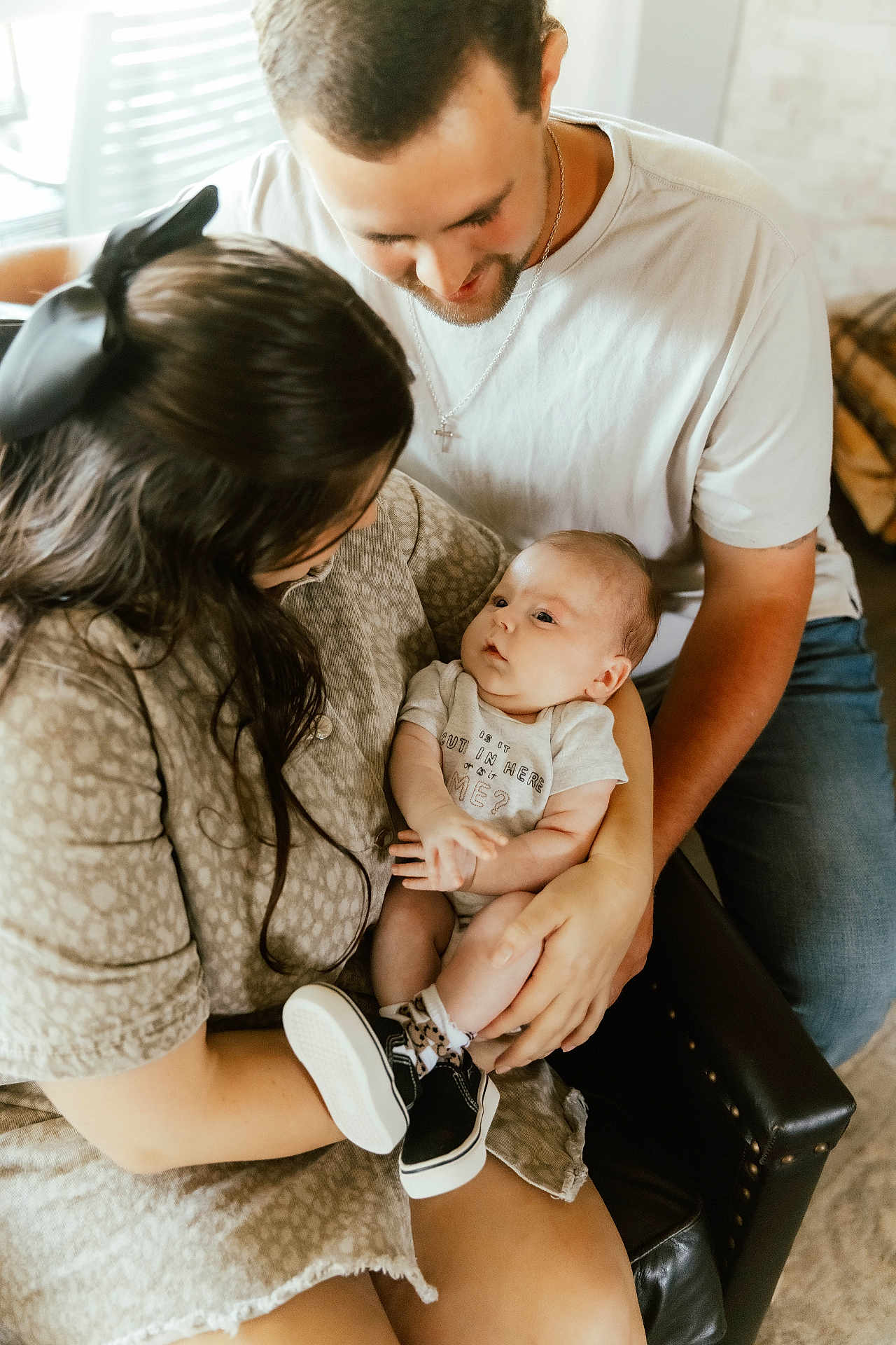 Everett is registered to the contest to win money with this photo: baby, woman, man, family, indoor, baby_clothing, sneakers, holding, love, happy, smiling, casual_clothing, armchair, portrait, people, affection, baby_socks, hair_bow, skin, gentle