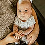 Everett is registered to the contest to win money with this photo: baby, infant, child, person, hands, arms, clothing, onesie, shoes, black_shoes, blue_eyes, closeup, portrait, indoor, seated, adult_hands, patterned_fabric, skin, cute, holding