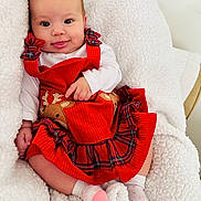 Génesis joined the competition — help win amazing prizes! baby, infant, red_dress, reindeer, plaid, white_blanket, cozy, cute, smiling, tongue_out, child, socks, soft_texture, indoor, portrait, happy, holiday, festive, person, seated