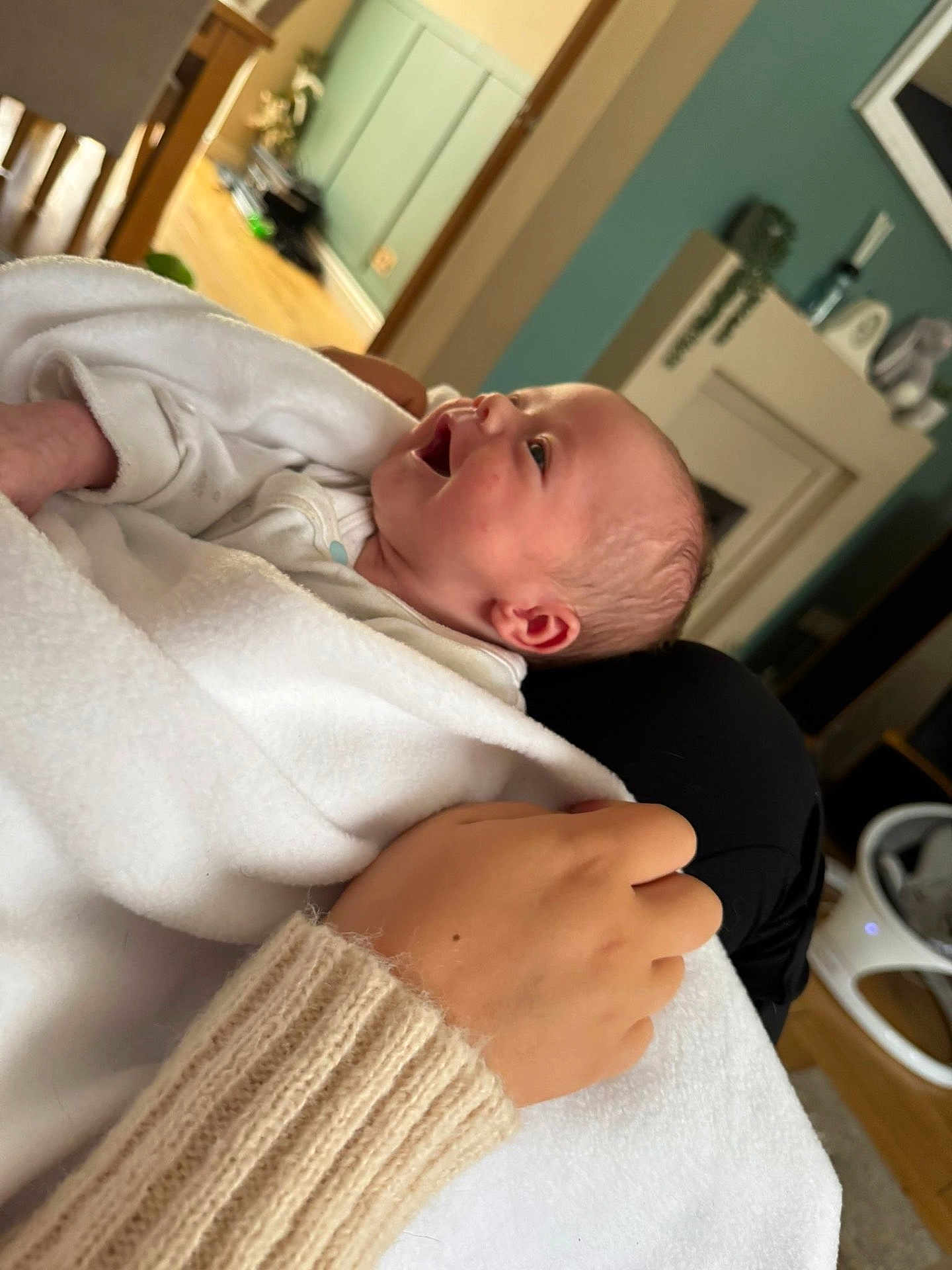 Lorenzo is registered to the contest to win money with this photo: baby, infant, blanket, hand, sleeve, knitted, smiling, happy, person, indoor, home, furniture, wooden_floor, cozy, child, newborn, portrait, care, comfort, warm