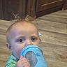 baby, child, blue_cup, floor, wooden_floor, kitchen, cabinet, toddler, hand, face, eyes, hair, indoor, drinking, holding, sippy_cup, curious, closeup, infant, chewing