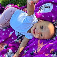 Daquila Debase is registered to the contest to win money with this photo: baby, infant, child, smiling, blanket, purple_blanket, grass, outdoors, onesie, lying_down, reaching_hand, face, head, eyes, portrait, playful, happy, sunlight, closeup, animal_print