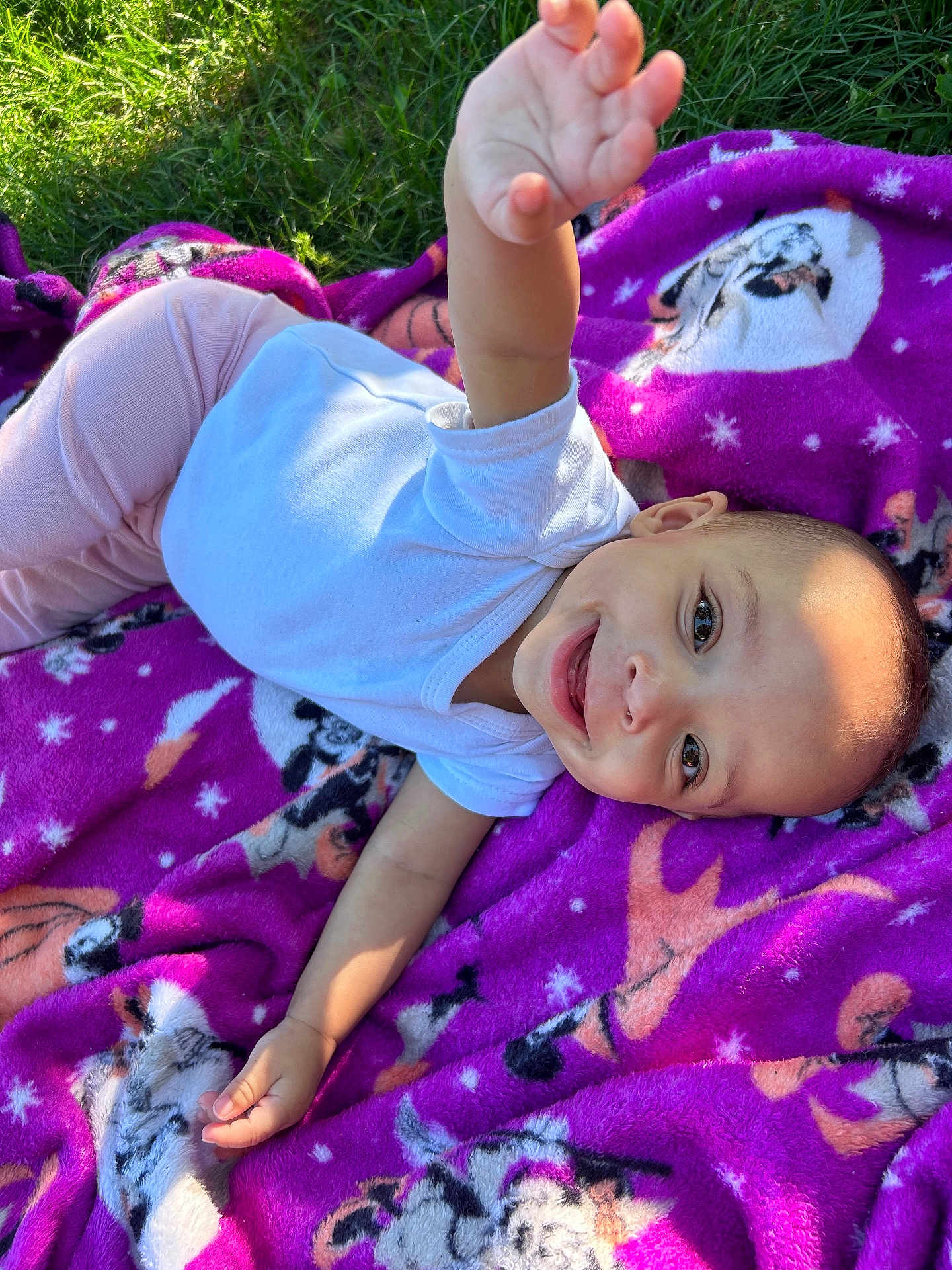 Daquila Debase is registered to the contest to win money with this photo: baby, infant, child, smiling, blanket, purple_blanket, grass, outdoors, onesie, lying_down, reaching_hand, face, head, eyes, portrait, playful, happy, sunlight, closeup, animal_print