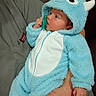baby, infant, blue_onesie, monster_costume, pacifier, hand, cute, fluffy, hood, horns, child, person, sitting, indoor, closeup, soft_texture, apparel, warm_clothing, portrait, adorable