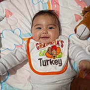 Rylann joined the competition — help win amazing prizes! baby, bedding, bib, blanket, child, cozy, crib, diaper, happy, indoor, infant, lion_toy, lying_down, nursery, onesie, plush_toy, portrait, smiling, thanksgiving, turkey