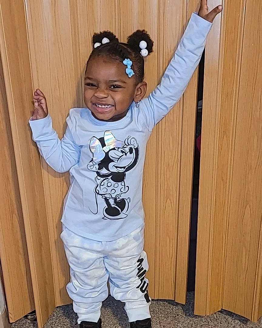 Aaliyah is registered to the contest to win money with this photo: baby_toddler_clothing, child, cool, costume, door, flooring, fun, gesture, happy, head, joy, outerwear, pattern, person, sleeve, smile, sportswear, standing, t_shirt, textile