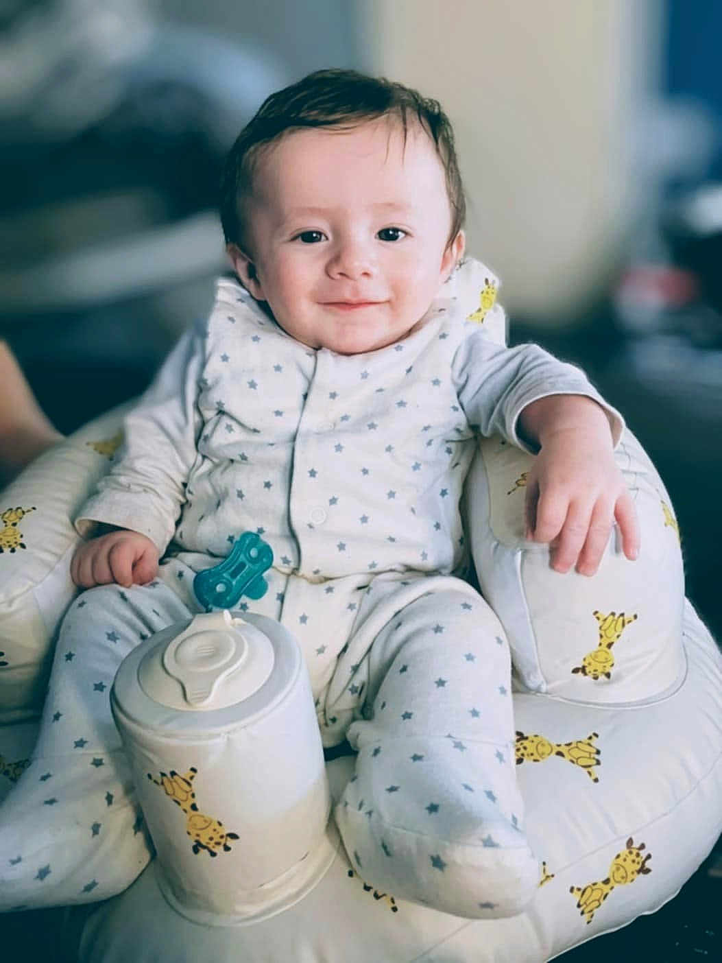 Billy-James joined the competition — help win amazing prizes! baby, child, infant, smile, face, pajamas, star_pattern, giraffe_pattern, cushion, seat, indoor, comfort, relaxed, cute, person, small_hand, soft_lighting, portrait, happy, clothing