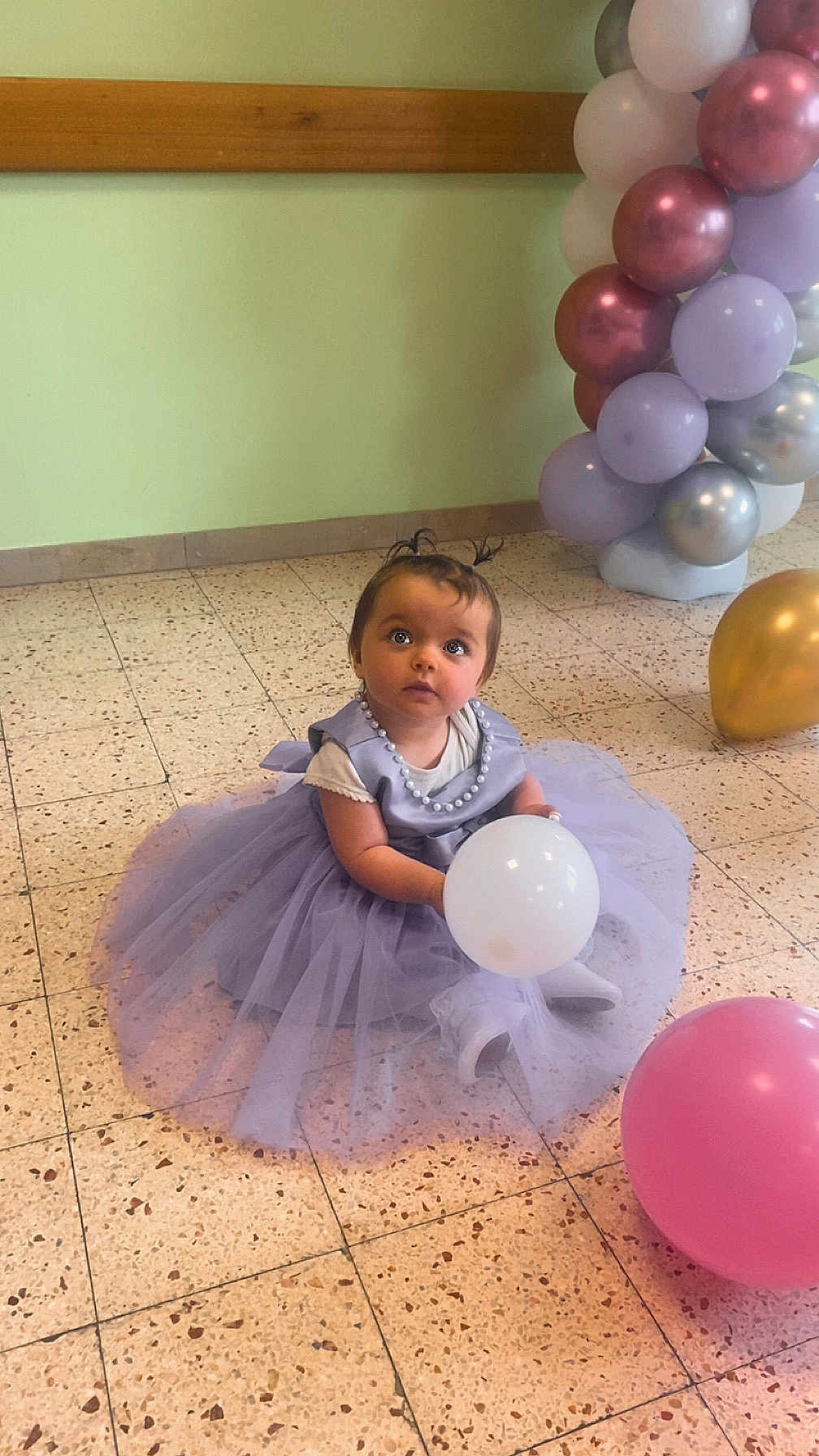 Aëlys participe au concours pour gagner de l'argent avec cette photo : baby, child, balloon, tutu, dress, floor, tiles, party, celebration, purple, lavender, pink_balloon, gold_balloon, white_balloon, beads, sitting, cute, indoor, curly_hair, decorations
