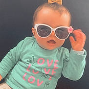 Aëlys participe au concours pour gagner de l'argent avec cette photo : baby, child, sunglasses, bow, shirt, love, sign_language, mint_green, pink, white, pants, couch, pillow, indoor, cute, smiling, hand, face, fashion, seated