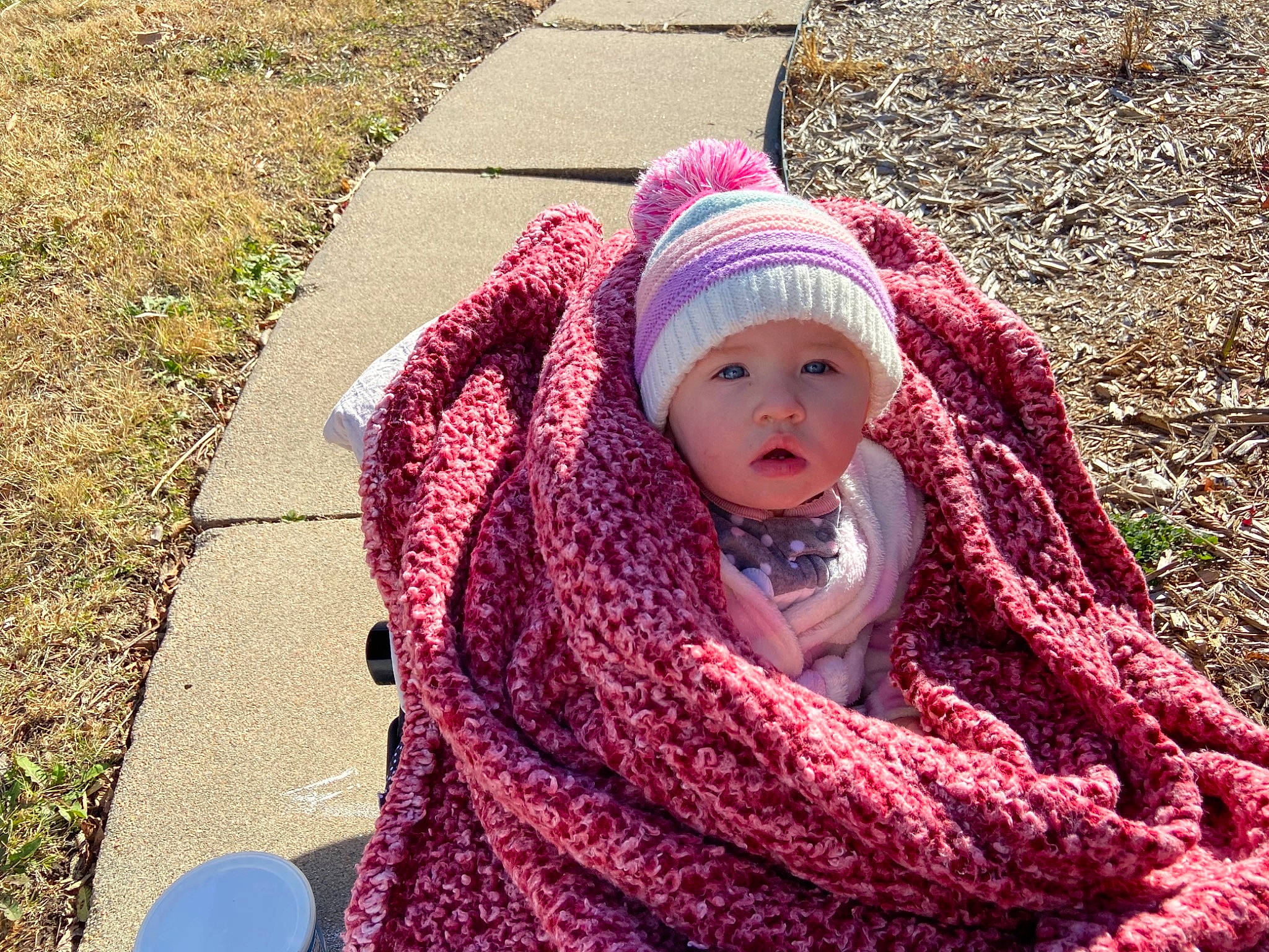 Astrid is registered to the contest to win money with this photo: baby, cap, child, crochet, fashion_accessory, grass, headgear, headwear, knit_cap, magenta, outerwear, pattern, people_in_nature, person, pink, purple, red, toddler, violet, winter