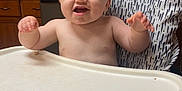 Levi joined the competition — help win amazing prizes! baby, high_chair, kitchen, refrigerator, magnet, photo, note, cabinet, countertop, smiling, child, food_tray, arm, face, furniture, indoor, person, expression, table, cute