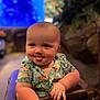 baby, child, tongue_out, shirt, flamingo_pattern, chair, indoor, aquarium, blurred_background, cute, portrait, smiling, happy, toddler, hands, seated, colorful, skin, face, eyes