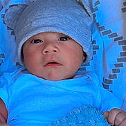 Alvarito is registered to the contest to win money with this photo: baby, infant, hat, blue_blanket, bedspread, clothing, face, person, child, cute, indoors, portrait, newborn, soft_texture, looking, lying_down, warm, cozy, small_hand, expression