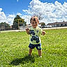 child, boy, toddler, smiling, outdoor, grass, playground, park, sunny, clouds, blue_sky, portrait, standing, shorts, t_shirt, sportswear, happy, daylight, residential_area, photography