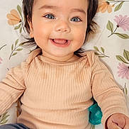 Aaliyah joined the competition — help win amazing prizes! baby, blue_eyes, child, closeup, clothing, cushion, cute, face, floral_pattern, hair, hand, happy, indoor, infant, lying_down, pants, portrait, skin, smiling, sweater