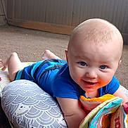 Abel is registered to the contest to win money with this photo: baby, infant, smiling, toy, play_mat, soft_book, pillow, indoor, carpet, child, blue_clothing, colorful, cute, happy, face, person, floor, playtime, young_child, toddler