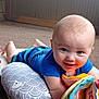 baby, infant, smiling, toy, play_mat, soft_book, pillow, indoor, carpet, child, blue_clothing, colorful, cute, happy, face, person, floor, playtime, young_child, toddler
