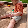 barefoot, casual, child, daytime, grass, hand, kid, leg, nature, outdoor, playing, sand, sandbox, shirt, shorts, summer, sunlight, toddler, toy, wooden_frame