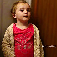 Alora joined the competition — help win amazing prizes! child, indoor, cardigan, pink_shirt, face, standing, portrait, young_child, expression, casual, cozy, clothing, person, human, background_blur, short_hair, looking_away, hand, light, warm_colors