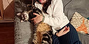 Sony a rejoint le concours — aidez-le/la à gagner de superbes lots ! woman, cat, couch, indoor, cozy, tabby_cat, white_sweater, striped_pants, wooden_floor, pillow, relaxed, pet, holding, smiling, long_hair, home, comfortable, furniture, happy, casual