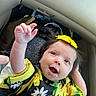 baby, child, smiling, happy, yellow_bow, floral_dress, hand, face, person, infant, cute, indoors, clothing, sitting, skin, head, hair, bright_colors, joy, expression