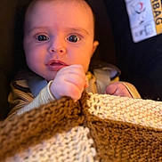 Maya participe au concours pour gagner de l'argent avec cette photo : baby, blanket, car_seat, child, face, hand, knitted_blanket, wide_eyes, curious, infant, seatbelt, closeup, portrait, indoor, safety_label, warm_lighting, expression, soft_texture, young_child, cute