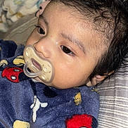 Ian is registered to the contest to win money with this photo: baby, pacifier, blanket, mickey_mouse, bed, striped_bedspread, curly_hair, infant, close_up, sleepwear, soft_texture, indoors, resting, child, young_child, face, head, cozy, comfort, cute