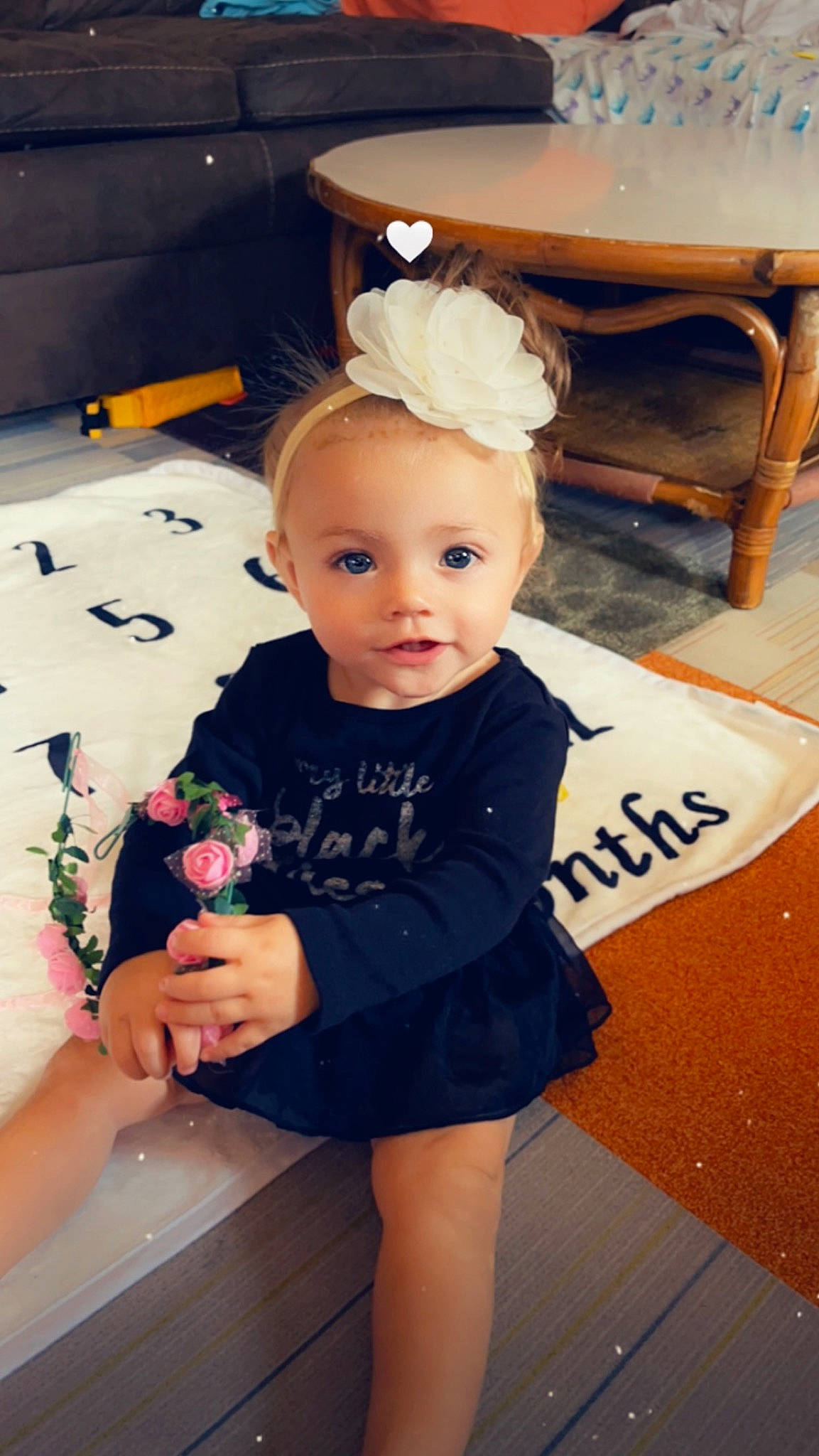 Brinley is registered to the contest to win money with this photo: baby, baby_toddler_clothing, cheek, child, eye, facial_expression, fashion_accessory, flooring, fun, happy, head, iris, person, room, sitting, skin, sleeve, t_shirt, toddler, white
