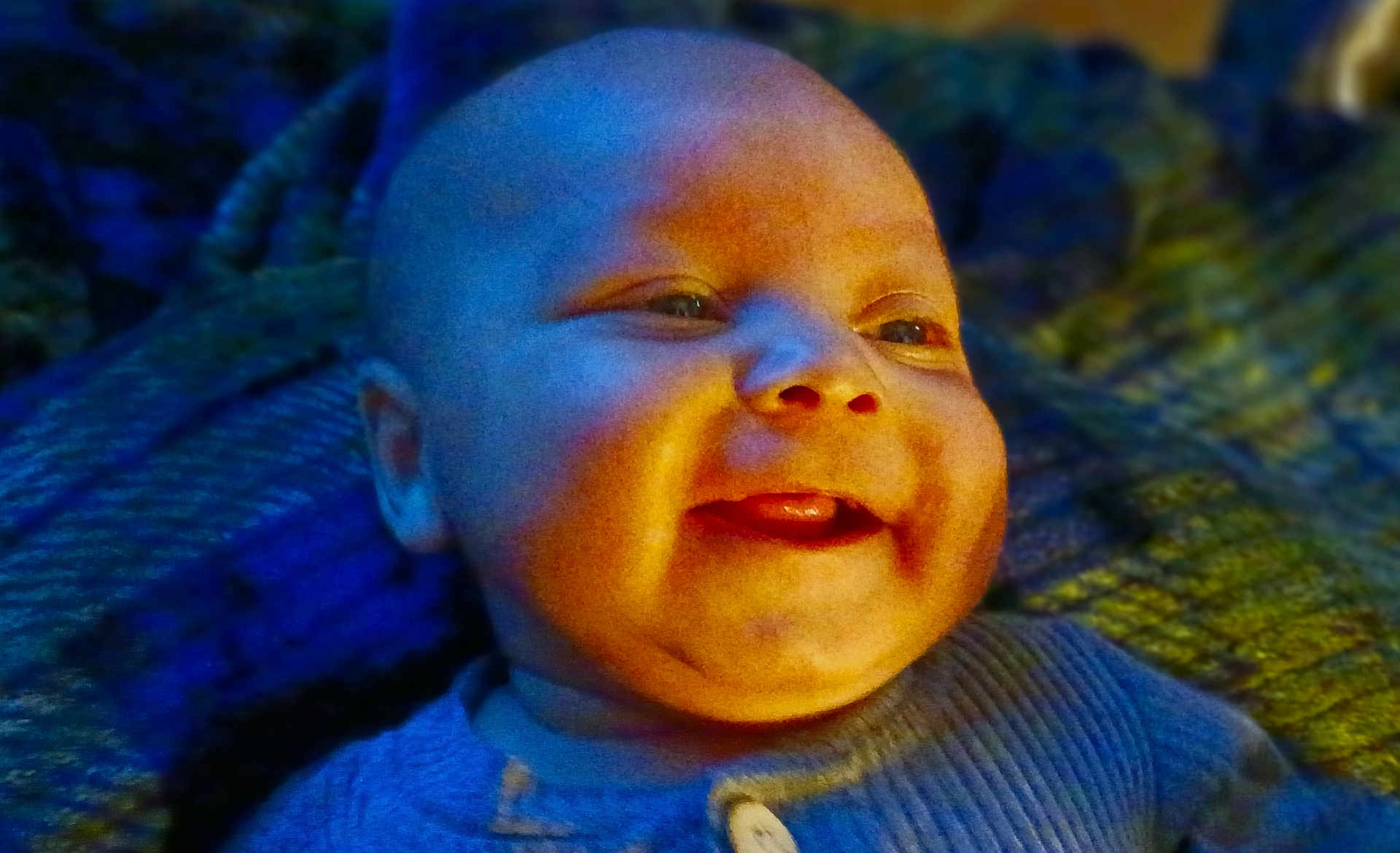 Zy'Iir joined the competition — help win amazing prizes! baby, smile, face, tongue, blue_clothing, blanket, texture, happy, infant, closeup, portrait, child, cute, warm_light, cool_light, indoors, expression, skin, head, young