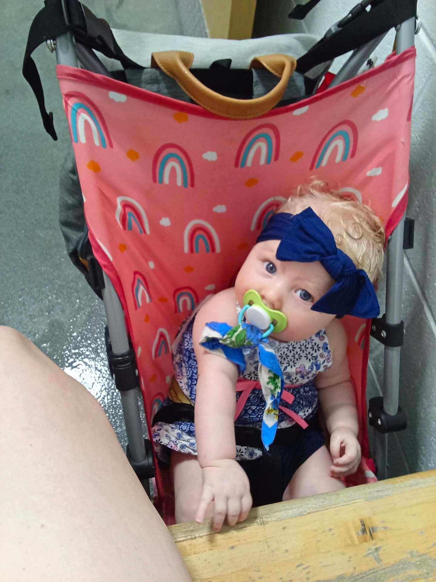 Zelpa joined the competition — help win amazing prizes! baby, child, stroller, pacifier, headband, bow, pink, rainbow_pattern, table, indoor, cute, curious, sitting, clothing, fabric, person, infant, hand, blue, face