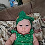 Zelpa is registered to the contest to win money with this photo: baby, child, green_headband, green_dress, couch, blanket, indoor, portrait, face, person, sitting, cute, infant, young_child, patterned_blanket, furniture, expressionless, wide_eyes, soft_lighting, home