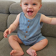 Maël a rejoint le concours — aidez-le/la à gagner de superbes lots ! baby, child, smile, happy, sitting, romper, blue_clothing, couch, furniture, indoor, cute, infant, face, skin, arm, foot, toes, eyes, head, person