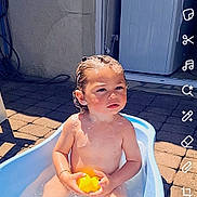 Nayden a rejoint le concours — aidez-le/la à gagner de superbes lots ! baby, bath_time, bathtub, child, curious_expression, daylight, door, outdoor, pavement, person, playful, rubber_duck, skin, soap_suds, summer, sunlight, toddler, toy, water, wet_hair