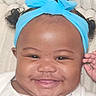 Blessing is registered to the contest to win money with this photo: baby, infant, child, portrait, smiling, happy, face, close_up, blue_bow, headband, curly_hair, dark_skin, eyes, cheeks, mouth, white_clothing, hand, indoor, blanket, candid
