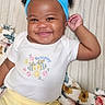 baby, child, infant, smiling, happy, portrait, lying_down, blue_headband, bow, white_shirt, yellow_pants, bee_design, floral_blanket, bed, indoor, face, eyes, arms, cute, photograph