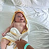 Larry is registered to the contest to win money with this photo: baby, towel, bed, hand, blanket, infant, white, yellow, person, skin, child, cute, lying_down, bedroom, soft, wrapped, expression, comfort, indoor, human