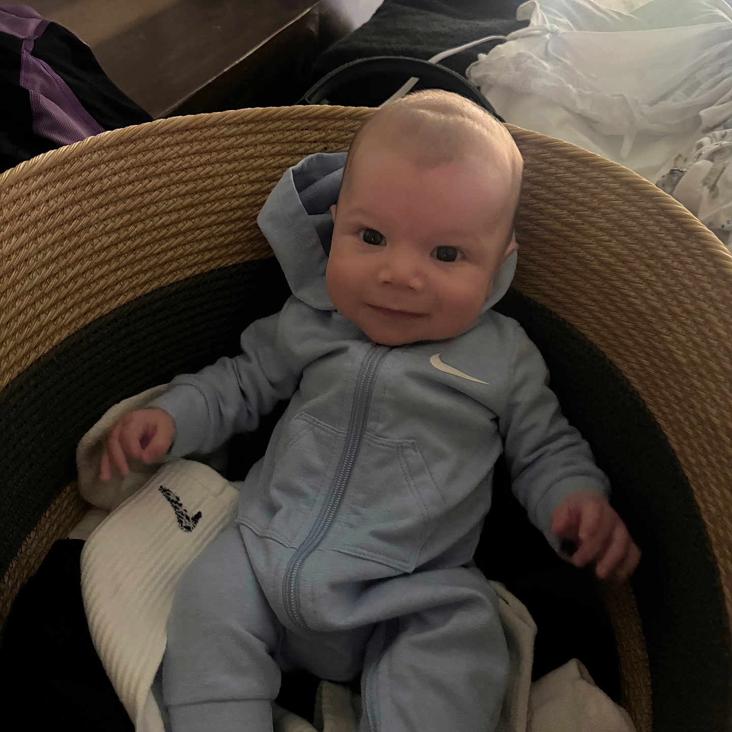 Larry joined the competition — help win amazing prizes! baby, infant, smile, face, onesie, nike, basket, blanket, clothing, indoor, child, cute, portrait, seated, happy, soft_lighting, home, fabric, newborn, cozy