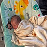 newborn, baby, blanket, sleeping, baby_bouncer, giraffe, monkey, bird, infant, cozy, cute, indoor, soft_texture, child, resting, wrapped, floor, wooden_floor, peaceful, toddler